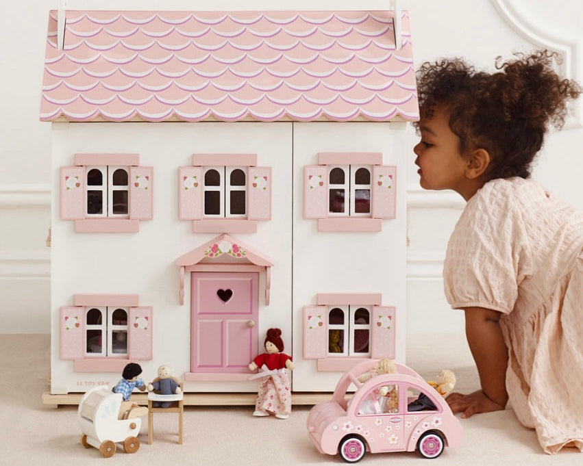 Child playing with a dollhouse and toys in a bright room